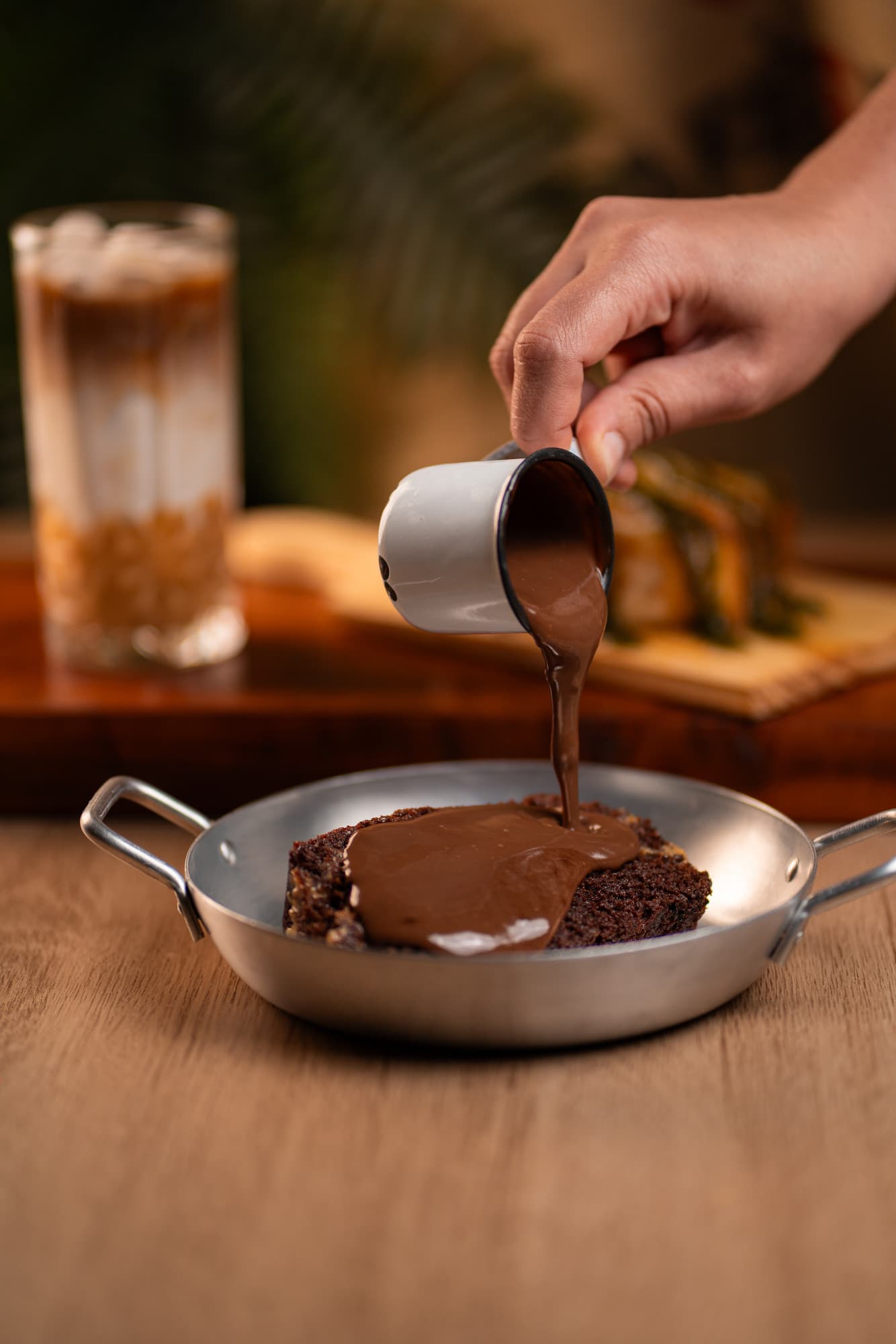 Bolo dos meus aniversários: calda de chocolate sendo despejada sobre a fatia de bolo, servida na frigideira.