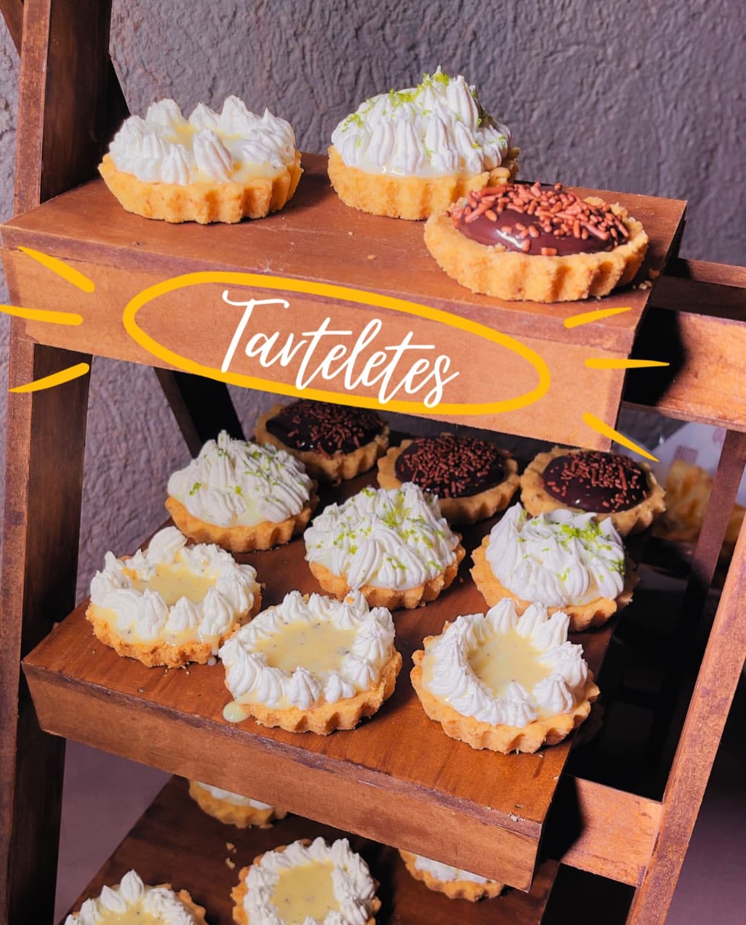 Café colonial: tarteletes de limão e de chocolate em prateleiras de madeira.