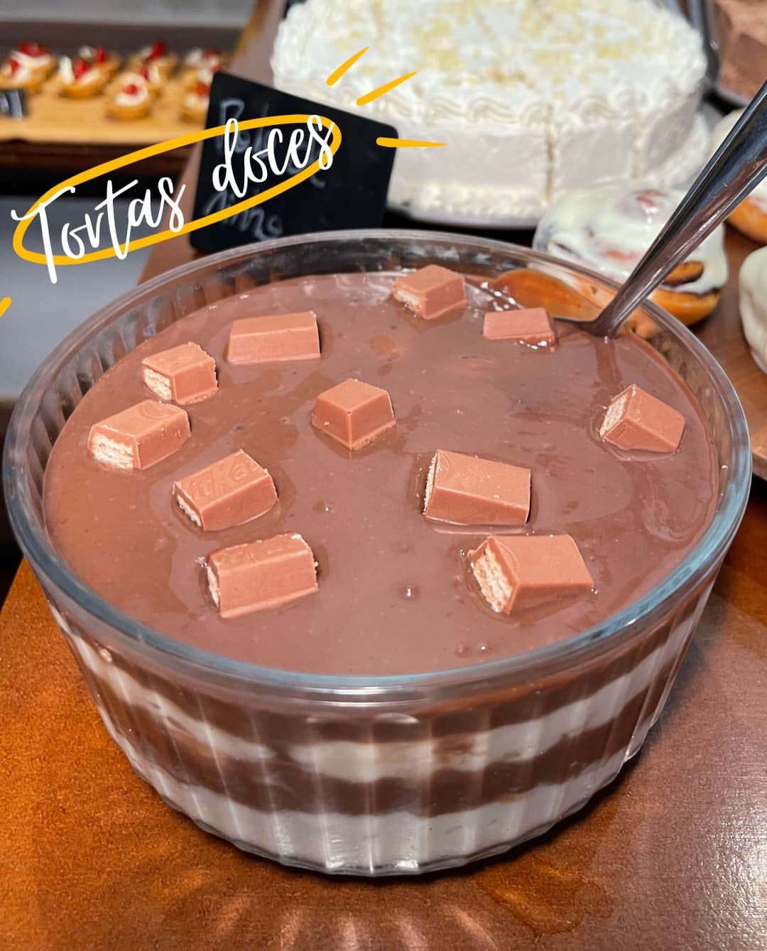 Café colonial: torta doce de chocolate com pedaços de wafer em travessa de vidro, com bolo branco ao fundo.