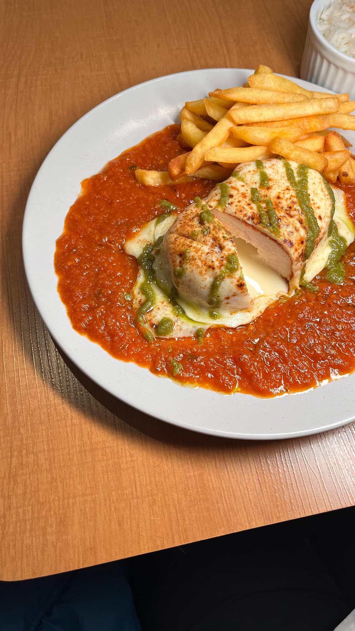 Parmegiana do Bistrô: peito de frango recheado com catupiry, molho de tomate, pesto de manjericão e fritas.